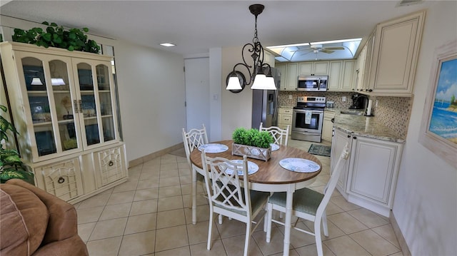 tiled dining room with ceiling fan, a skylight, and sink