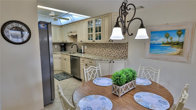 kitchen featuring appliances with stainless steel finishes, pendant lighting, light stone counters, and cream cabinets