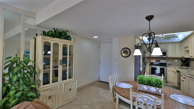 kitchen with stainless steel appliances, light stone countertops, sink, and cream cabinetry