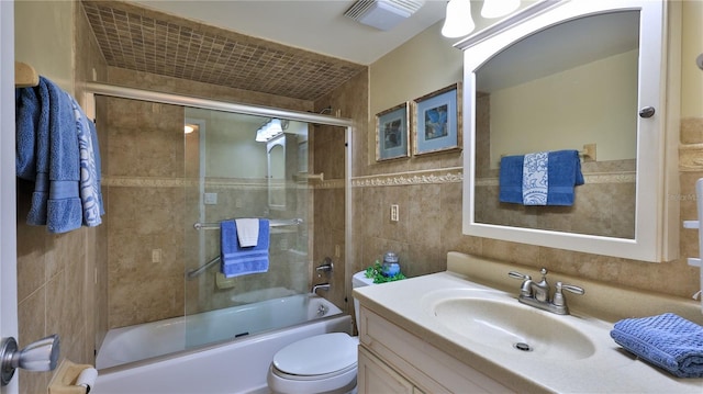 full bathroom with toilet, vanity, shower / bath combination with glass door, and tile walls