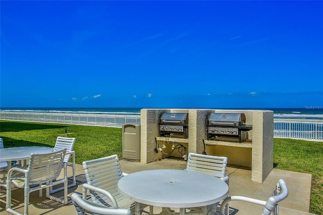 view of patio with a grill, a beach view, and a water view