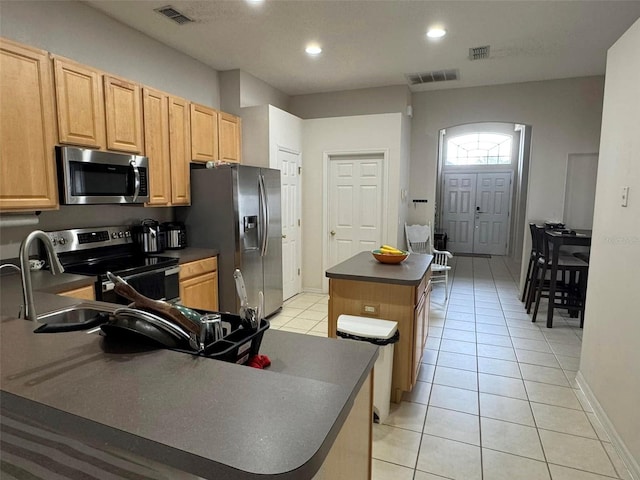 kitchen featuring appliances with stainless steel finishes, light tile patterned flooring, and a kitchen island