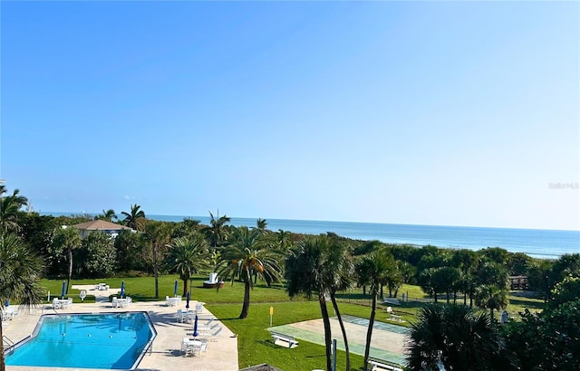 view of swimming pool with a patio area, a yard, and a water view