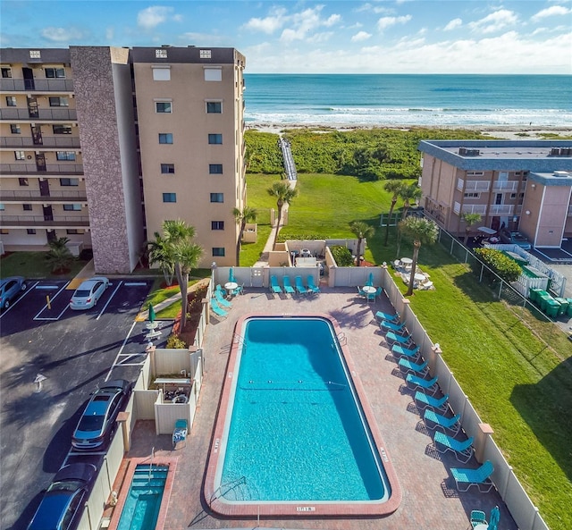 view of swimming pool featuring a view of the beach, a patio, and a water view