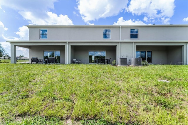 rear view of property with central AC unit and a yard