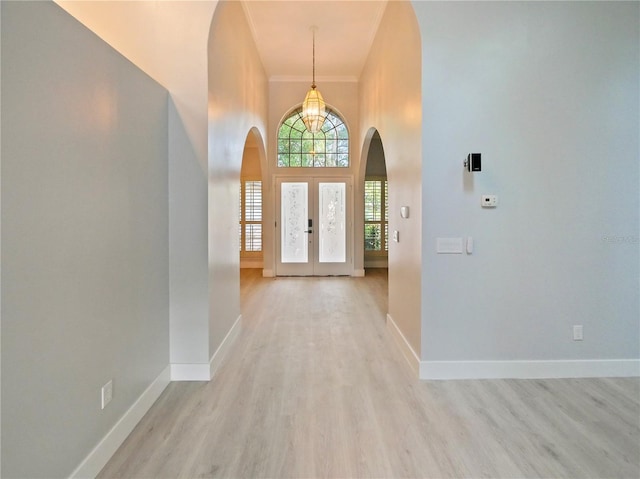 entryway featuring french doors, a towering ceiling, and light hardwood / wood-style floors