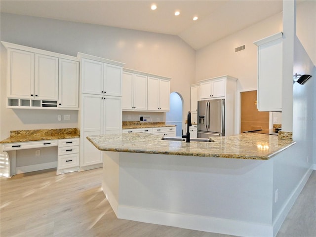 kitchen with white cabinetry, sink, light stone countertops, stainless steel fridge with ice dispenser, and kitchen peninsula