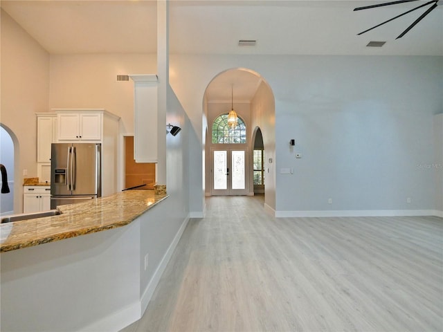 kitchen with white cabinetry, french doors, light stone countertops, stainless steel refrigerator with ice dispenser, and light hardwood / wood-style floors