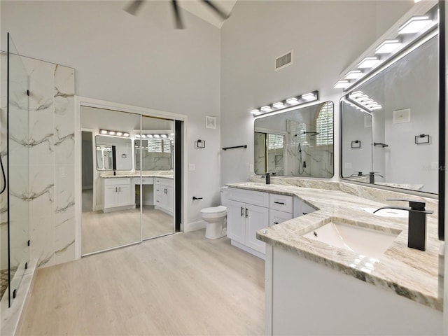 bathroom featuring a high ceiling, a shower, toilet, vanity, and hardwood / wood-style flooring