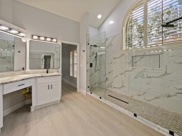 bathroom featuring hardwood / wood-style floors, vanity, a tile shower, and lofted ceiling