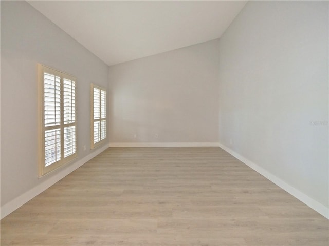 spare room with light hardwood / wood-style flooring and lofted ceiling