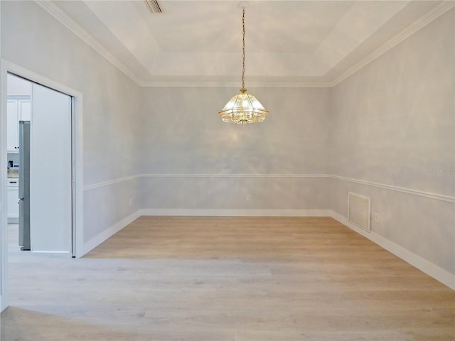 unfurnished dining area featuring light wood-type flooring and a tray ceiling