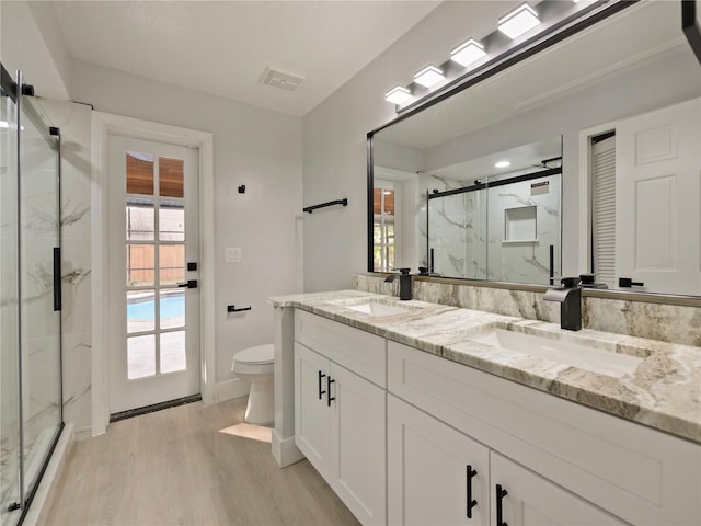 bathroom with hardwood / wood-style floors, vanity, toilet, and an enclosed shower