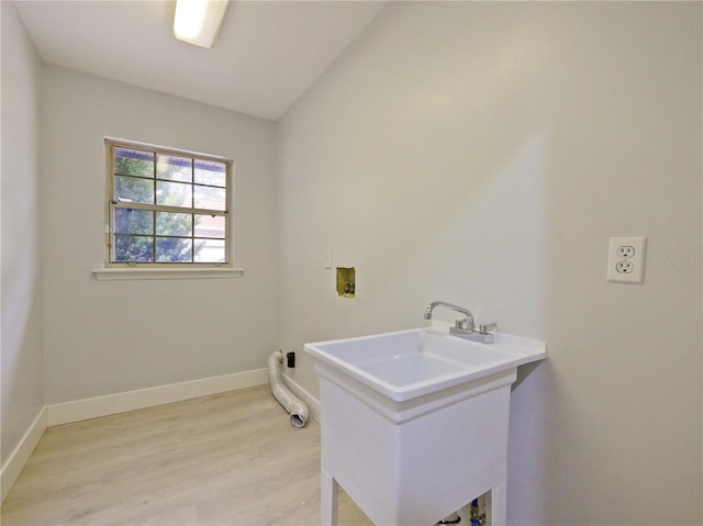 clothes washing area with hookup for a washing machine, light hardwood / wood-style floors, and sink