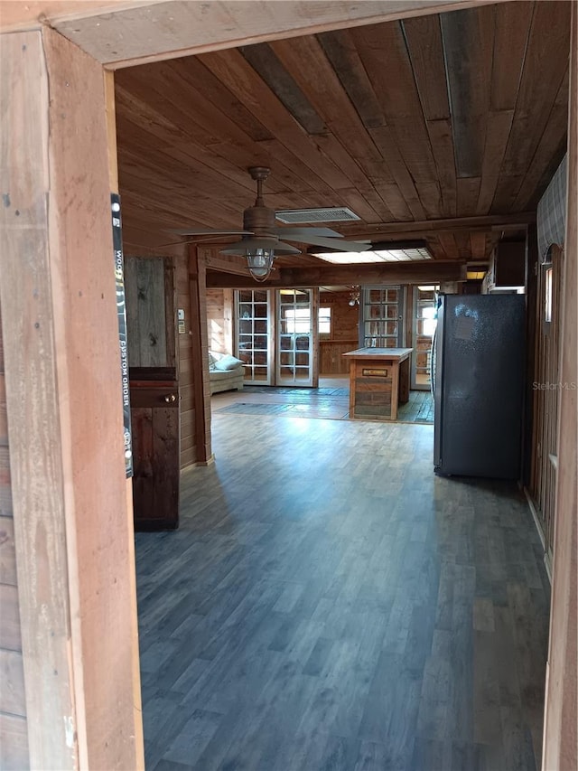 interior space featuring wooden ceiling, stainless steel fridge, dark hardwood / wood-style flooring, and wood walls