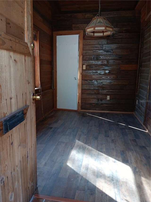 unfurnished dining area featuring wooden walls and dark hardwood / wood-style floors