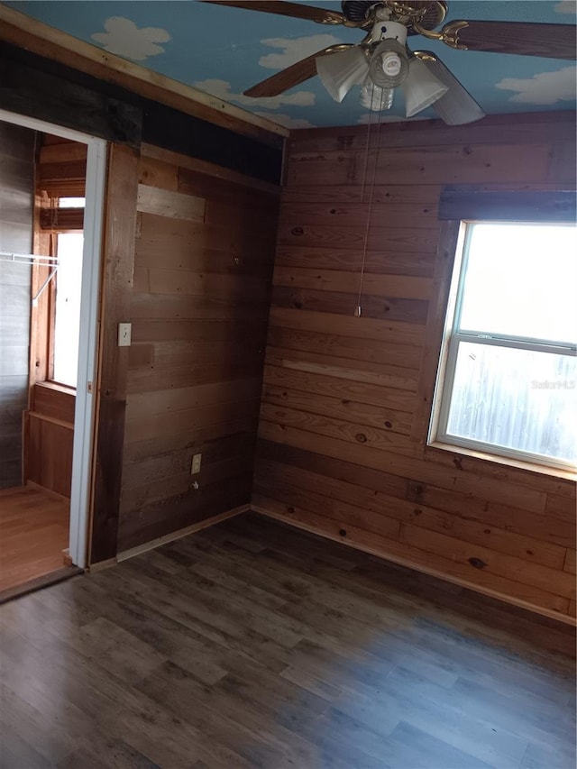 spare room featuring ceiling fan, wooden walls, and wood-type flooring