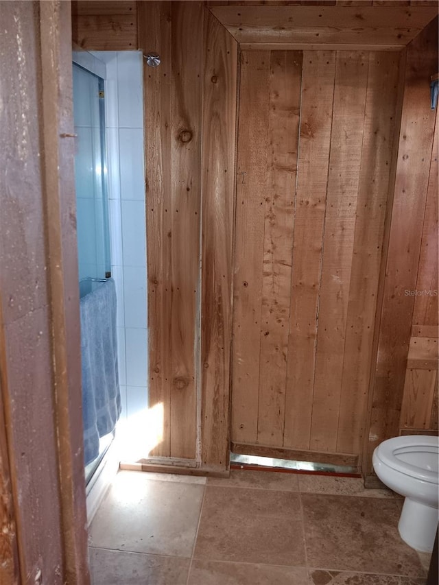 bathroom featuring toilet and wood walls