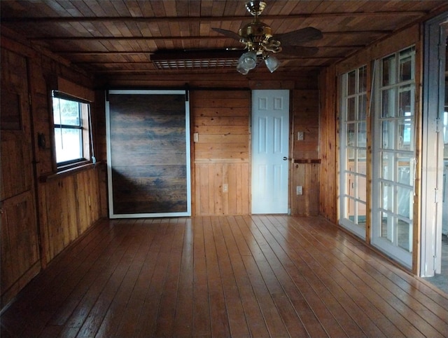 empty room with wood-type flooring, wooden walls, ceiling fan, and wood ceiling