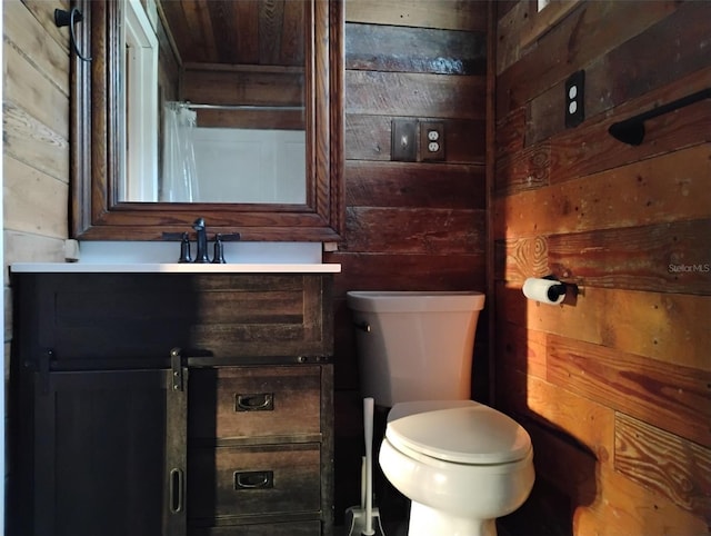 bathroom with vanity, toilet, and wood walls