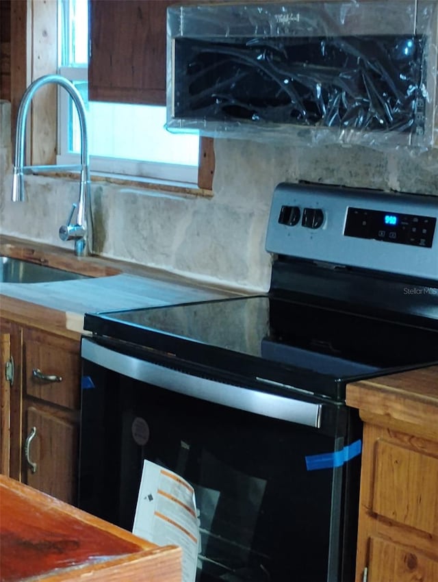 718 New York St, Clearwater, FL 33756 - kitchen featuring range with electric cooktop, a sink, and brown cabinets