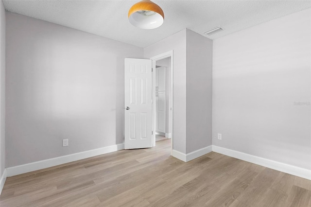 spare room with light hardwood / wood-style flooring and a textured ceiling