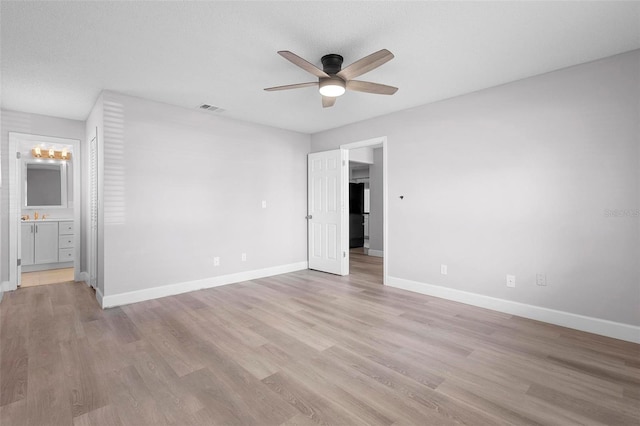 empty room with a textured ceiling, light wood-type flooring, and ceiling fan