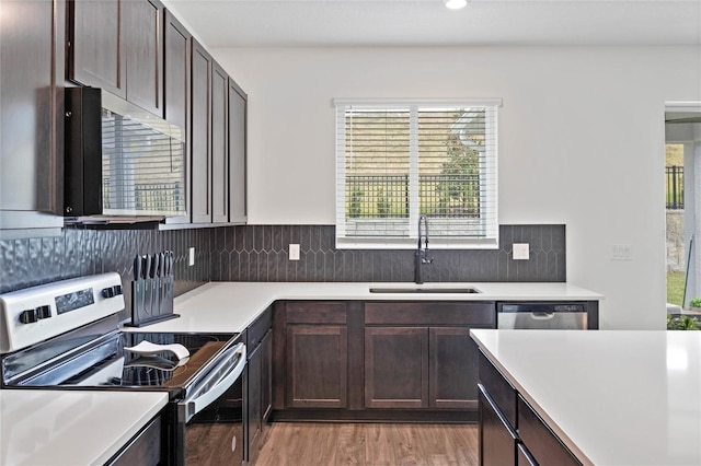 kitchen featuring sink, decorative backsplash, appliances with stainless steel finishes, dark brown cabinets, and light hardwood / wood-style floors