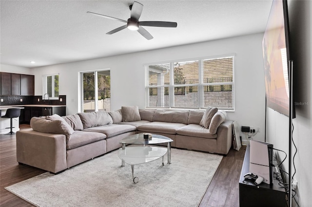 living room featuring dark hardwood / wood-style floors, ceiling fan, and sink