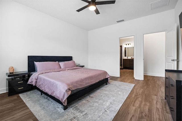 bedroom featuring ensuite bath, ceiling fan, and dark wood-type flooring