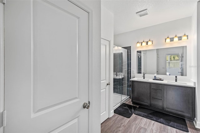 bathroom featuring hardwood / wood-style flooring, vanity, an enclosed shower, and a textured ceiling