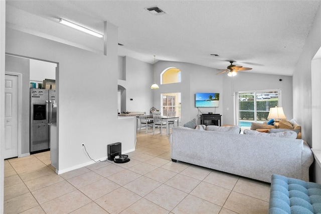 living area with vaulted ceiling, light tile patterned floors, visible vents, and ceiling fan