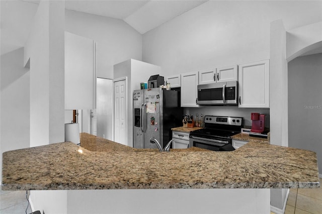 kitchen with stainless steel appliances, arched walkways, a peninsula, light tile patterned floors, and light stone countertops