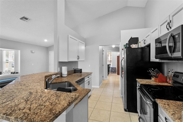 kitchen with visible vents, lofted ceiling, stone countertops, a sink, and appliances with stainless steel finishes