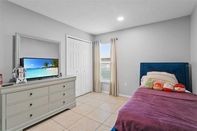 bedroom with light tile patterned floors, a textured ceiling, and baseboards