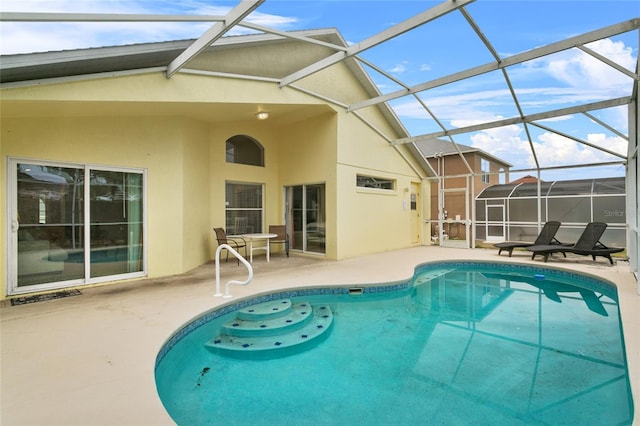 rear view of house with a lanai, a patio area, an outdoor pool, and stucco siding