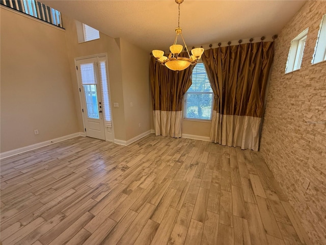 unfurnished room with light hardwood / wood-style flooring, plenty of natural light, and a chandelier