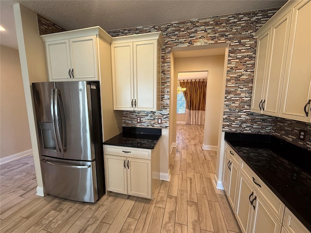 kitchen with a textured ceiling, stainless steel fridge with ice dispenser, light wood-type flooring, and tasteful backsplash