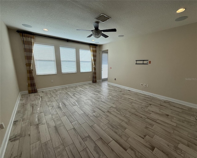 empty room featuring ceiling fan, light wood-type flooring, and a textured ceiling