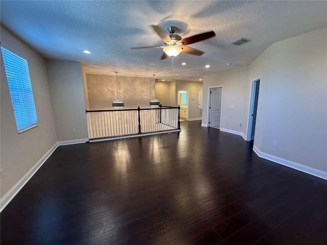 spare room with dark wood-type flooring, a textured ceiling, and ceiling fan