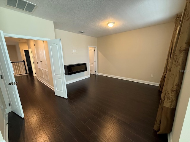 unfurnished living room with a textured ceiling and dark hardwood / wood-style flooring