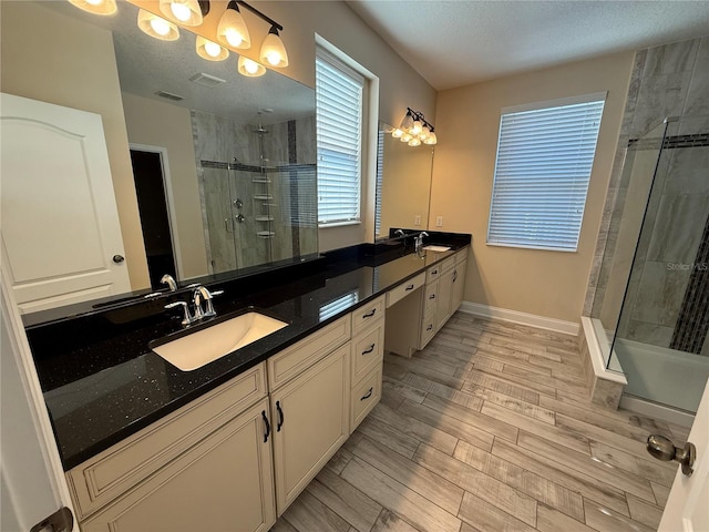 bathroom featuring a textured ceiling, a shower with shower door, and vanity