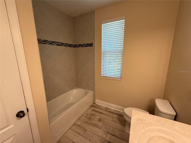 bathroom with toilet, tiled shower / bath, and a healthy amount of sunlight