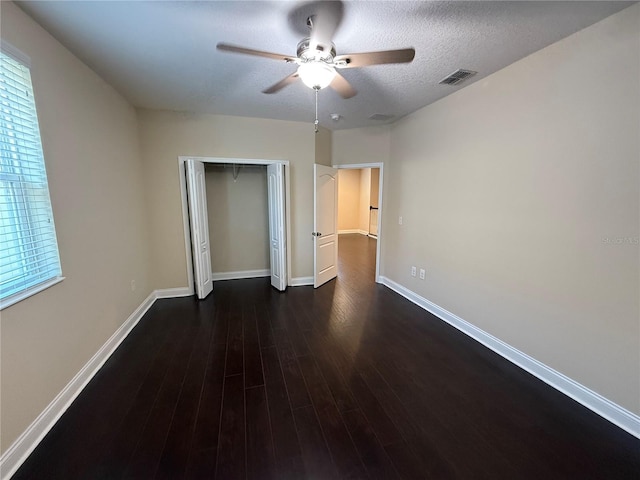 unfurnished bedroom featuring ceiling fan, dark hardwood / wood-style flooring, a closet, and a textured ceiling