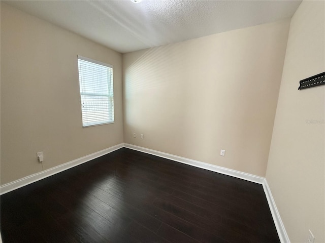 spare room with dark wood-type flooring and a textured ceiling