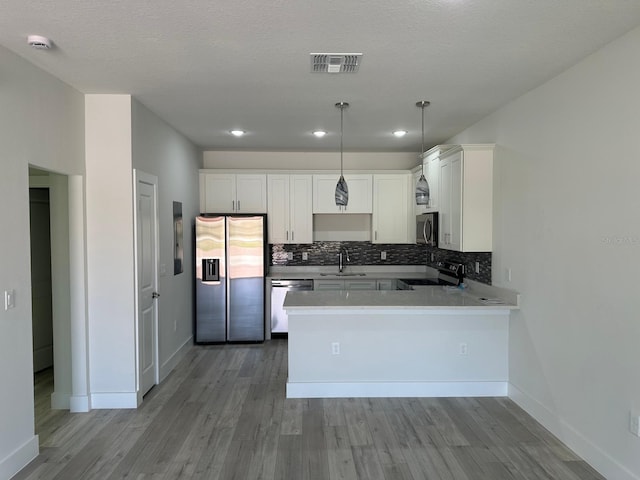 kitchen with sink, stainless steel appliances, kitchen peninsula, and white cabinetry