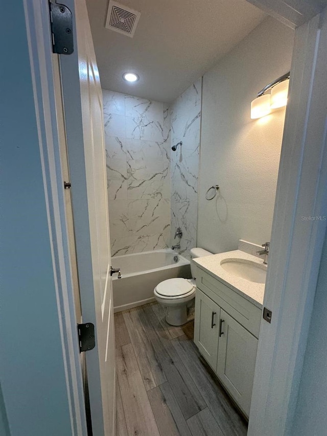 full bathroom featuring toilet, hardwood / wood-style flooring, tiled shower / bath, and vanity