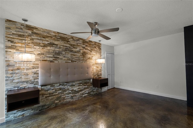 unfurnished living room featuring ceiling fan and a textured ceiling