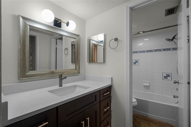 full bathroom with vanity, toilet, a textured ceiling, and tiled shower / bath combo