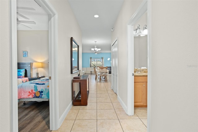 hallway with light tile patterned flooring and an inviting chandelier